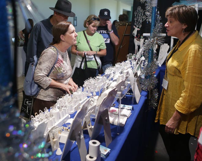 Sandra Shader of Shader Jewelry and Gifts helps customer Rebecca Valle at the Holly Fair on Friday.