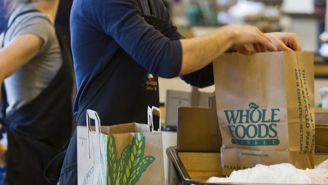 Whole Foods Market employee Adam Theall bags a customer's food on Wednesday, Feb. 13, 2013.