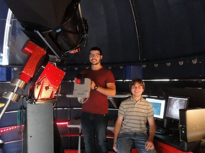 Embry-Riddle Aeronautical University space physics student Gabriel Gonzalez, left, holds a digital CCD camera and Creekside Observatory Assistant Forrest Gasdia sits next to the telescope computer controls in the observatory on campus. Gonzalez is tracking the Comet ISON for a school project.