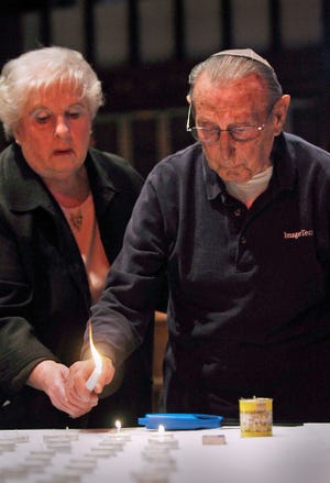 Holocaust survivor Israel Geller, right, 88, and his wife Marilyn light memorial candles during the Yom HaShoah service to remember the Holocuast at Temple Beth Abraham in Canton, Wednesday, April 18, 2012. Geller, a Canton resident, said he was imprisoned in six concentration camps, including Auschwitz, before being liberated by American soldiers in 1945.Photo: Amelia Kunhardt/The Patriot Ledger