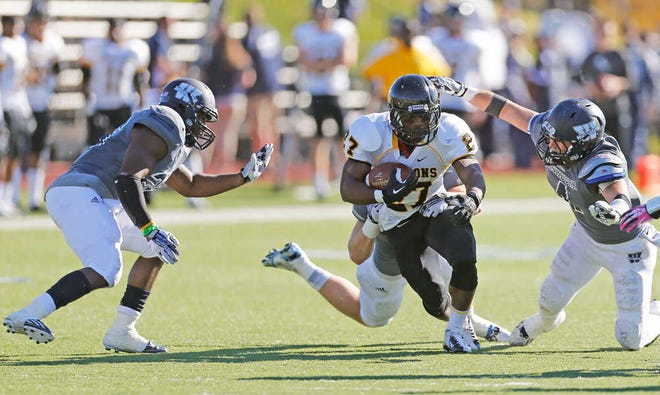 Missouri Western's Dominic Thomas drags one Washburn defender as Willie Williams, left, and Ryan Macken, right, swoop in to help make the stop during the first half of Saturday's game at Yager Stadium. Williams and the Griffons held on for a 34-31 victory.