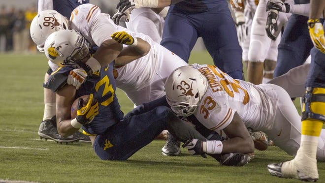 Texas Longhorns' Desmond Jackson, 99, and Steve Edmond, 33, tackle West Virginia's Charles Sims in the second half of the NCAA college football game at Mountaineer Field at Milan Puskar Stadium in Morgantown, W.V., on Saturday, Nov. 9, 2013.