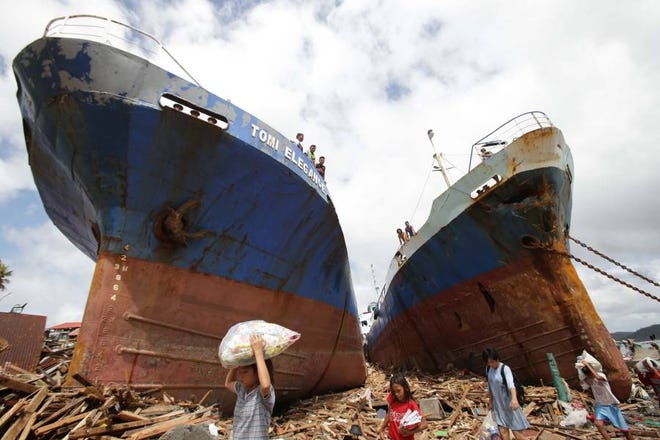 Survivors pass by two large boats after they were washed ashore by strong waves caused by Typhoon Haiyan in Tacloban city, Leyte province central Philippines on Sunday. Typhoon Haiyan, one of the strongest storms on record, slammed into six central Philippine islands on Friday leaving a wide swath of destruction and thousands of people dead.
