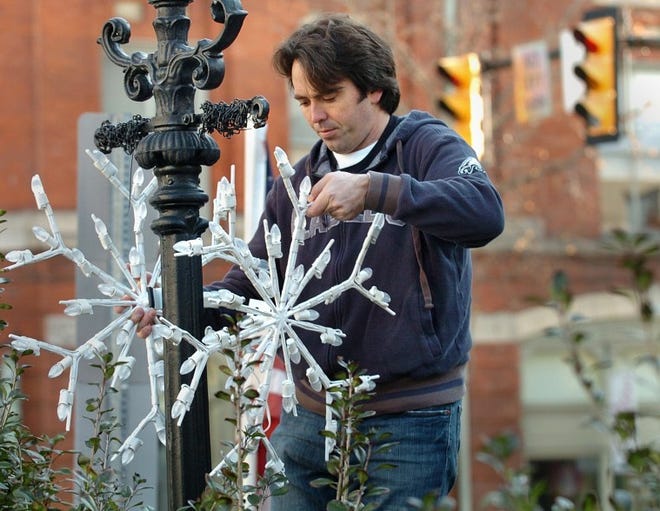 Doyle Walton of Doylestown hangs the first snowflake holiday decoration of the 2011 season on State Street in this file photo.