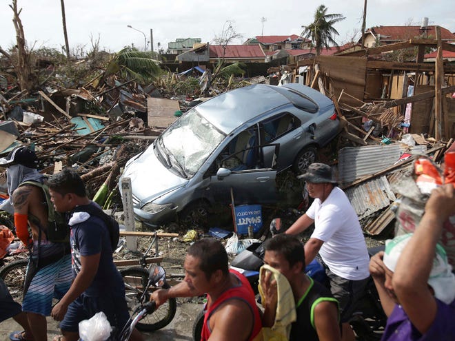 Survivors move past the damages caused by Typhoon Haiyan in Tacloban city, Leyte province central Philippines on Monday.