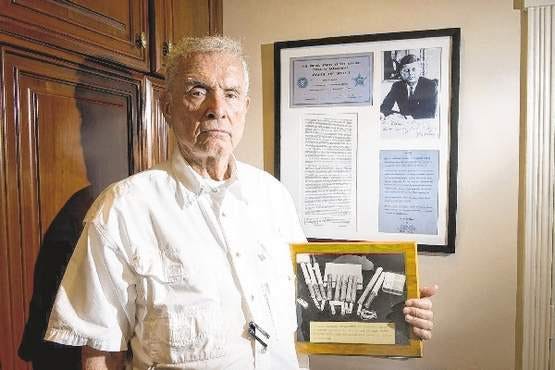 Robert Rust, formerly the assistant U.S. attorney, holds sticks of dynamite near documents Friday in his Miami home pertaining to President-elect John F. Kennedy's attempted assassination in December 1960 by Richard Pavlick. (More Content Now photo)