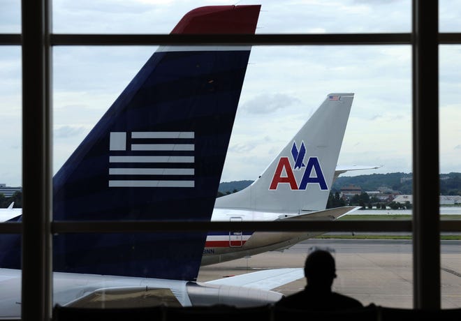 In this Tuesday, Aug. 13, 2013, file photo, an American Airlines plane and a US Airways plane are parked at Washington’s Ronald Reagan National Airport in Washington. While American Airlines and US Airways have cleared the last major hurdle to merging, but it will be several months , if not years, before passengers see any significant impact.