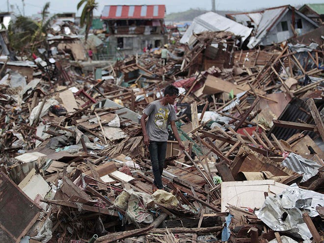 A Filipino man walks among debris from damaged homes at typhoon-hit Tacloban city, Leyte province, central Philippines on Wednesday, Nov. 13, 2013. Typhoon Haiyan, one of the strongest storms on record, slammed into six central Philippine islands on Friday leaving a wide swath of destruction.