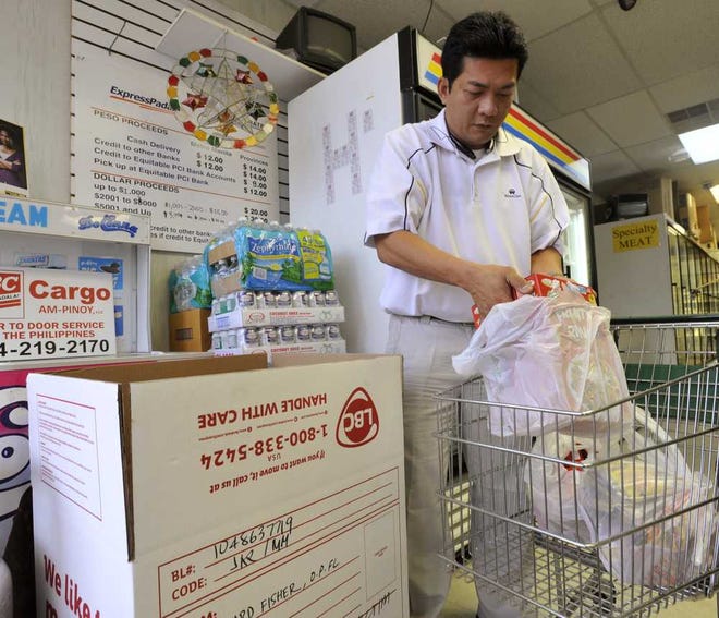 Will.Dickey@Jacksonville.com--11/12/13--Manny Eco, owner of JGM Asian Market on 103rd Street, sorts through food donations for the victims of Typhoon Haiyan in the Philippines Tuesday, November 12, 2013 in Jacksonville, Florida. The box is the 15th that has been filled since the typhoon hit. (The Florida Times-Union, Will Dickey)