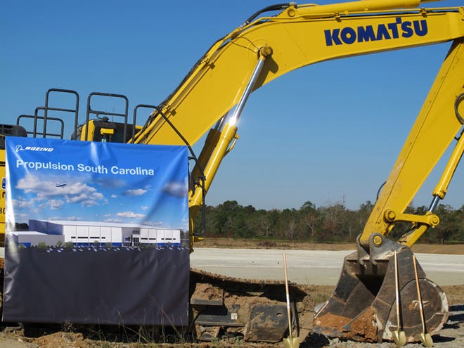A banner on a construction shovel shows a rendering of Boeing's planned South Carolina propulsion plant during a groundbreaking for the facility Thursday in North Charleston. The new plant, which should be completed in about a year, will be built on the site in the background.