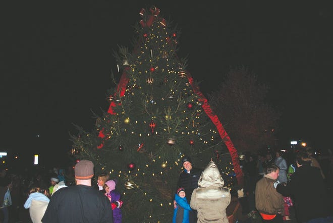 Residents get their photos taken in front of the Tree of Dreams after it was lit on Friday night.