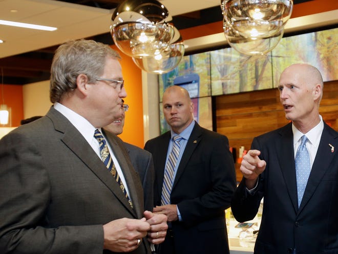 Gov. Rick Scott, right, talks to Marshall M. Criser III, left, AT&T Florida-President, during the opening of a new AT&T store, Wednesday, Oct. 30, 2013, in Miami. AT&T announced it is hiring more than 165 workers in the Miami-Fort Lauderdale area, including more than 50 new positions. The South Florida openings are among the more than 600 statewide announced today by AT&T. (AP Photo/Alan Diaz)