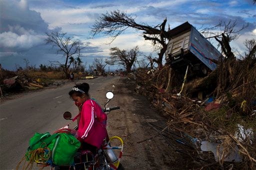 A woman rests on a roadside with her family's belongings near the Typhoon Haiyan ravaged town of Tacloban, central Philippines on Wednesday, Nov. 13, 2013. Typhoon Haiyan, one of the most powerful storms on record, hit the country's eastern seaboard on Friday, destroying tens of thousands of buildings and displacing hundreds of thousands of people. (AP Photo/David Guttenfelder)