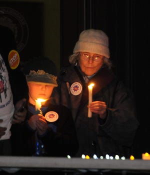 From left, Duncan Burnside, 10, of Wayland, and Lillian Corti, of Weston, hold candles during a vigil for gun violence victims on the steps of Town Hall on Thursday evening in Framingham.