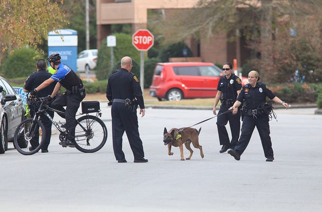 Policemen on bikes and dogs come back to the scene of the bank robbery Friday afternoon after patrolling the neighborhood for the suspect.