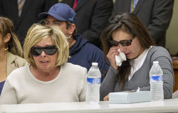 Susan McStay, left, mother of victim Joseph McStay, listens during a news conference at the San Bernardino County, Calif., sheriff's headquarters.