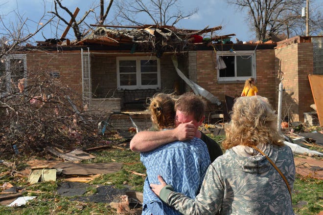 Ray Baughman embraces family Sunday after his home was destroyed by a tornado that left a path of devastation through the north end of Pekin, Ill. Intense thunderstorms and tornadoes swept across the Midwest on Sunday, causing extensive damage in several central Illinois communities while sending people to their basements for shelter.