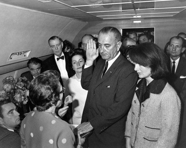 In this Friday, Nov. 22, 1963, photo from the White House via the John Fitzgerald Kennedy Library in Boston, Lyndon B. Johnson is sworn in as president as Jacqueline Kennedy stands at his side in the cabin of the presidential plane on the ground at Love Field in Dallas. Judge Sarah T. Hughes, a Kennedy appointee to the Federal court, left, administers the oath. In background, from left are, Associate Press Secretary Malcolm Kilduff, holding microphone; Jack Valenti, administrative assistant to Johnson; Rep. Albert Thomas, D-Texas.; Lady Bird Johnson; and Rep. Jack Brooks, D-Texas.
