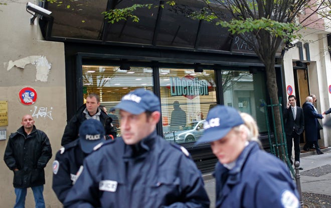 Police officers stand outside Liberation newspaper office Monday in Paris, after a gunman opened fire in the lobby, wounding a photographer's assistant before fleeing. Fabrice Rousselot, editor of the daily newspaper Liberation said the 27-year-old victim was in serious condition.