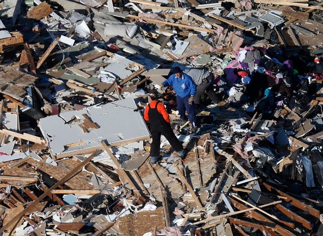 In this aerial view on Monday, two men walk through what is left of a home that was destroyed by a tornado that hit the western Illinois town of Washington on Sunday. It was one of the worst-hit areas after intense storms and tornadoes swept through Illinois.