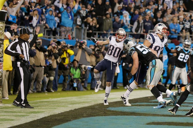 An official, left, reaches for his flag as Carolina Panthers' Luke Kuechly (59) hits New England Patriots' Rob Gronkowski (87) in the end zone on the last play of an NFL football game in Charlotte, N.C. They ruled no penalty on the play.