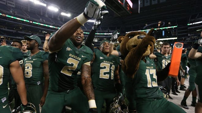 Baylor running back Johnny Jefferson (2) celebrates the Bears’ 63-34 victory over Texas Tech with a teammate and Baylor’s mascot, Bruiser. The Bears are undefeated and ranked No. 4 in the BCS standings.