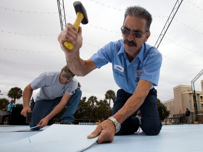 Bill McCaslin, left and Edwin Solero, right, with the City of Ocala Facilities, use rubber mallets to assemble panels for the ice rink at the City of Ocala's downtown skating rink Tuesday morning, November 19, 2013.