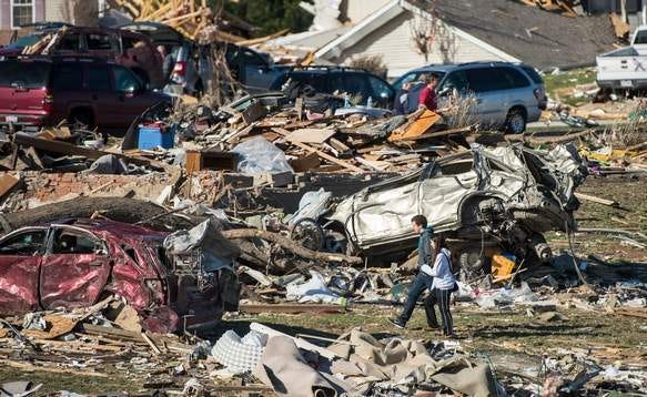 Demolished cars line the path as homeowners dig out what they can Tuesday after more than 1,000 homes were devastated by a F4 tornado that passed through Sunday. The twister was the most powerful to hit Illinois since 1885 with wind speeds greater than 200 mph.