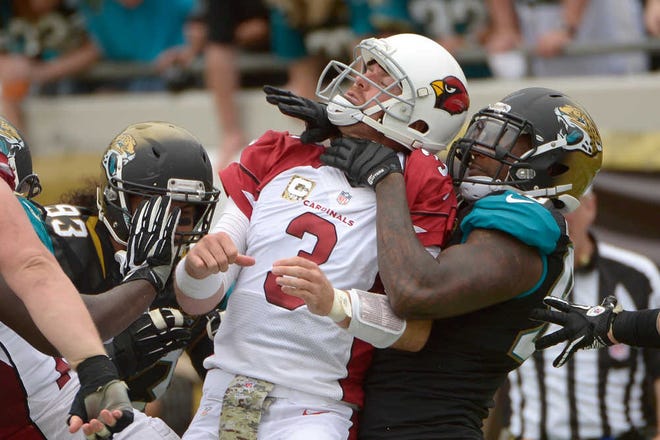 Arizona Cardinals quarterback Carson Palmer (3) is sandwiched between Jacksonville Jaguars defensive end Tyson Alualu (93) and defensive end Andre Branch, right, after throwing a pass during the first half of an NFL football game in Jacksonville, Fla., Sunday, Nov. 17, 2013.(AP Photo/Phelan M. Ebenhack)