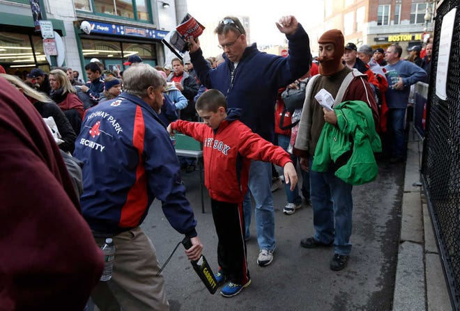 FILE - In this Oct. 30, 2013 file photo, Jeffrey Corbett, top, and his son Joseph, 9, center, both of Arlington, Mass., raise their arms as they pass through security outside Fenway Park before Game 6 of baseball's World Series between the Boston Red Sox and St. Louis Cardinals, in Boston. Baseball fans should expect to go through a metal detector to see their team play in 2014. MLB security director John Skinner says at a panel discussion at Harvard that the commissioner's office plans to recommend walkthrough metal detectors. (AP Photo/Steven Senne, File)