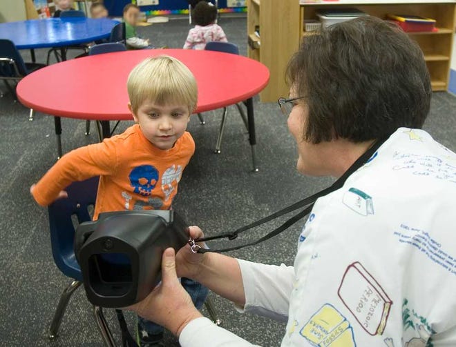 Carrie Enick, the sole nurse for Baldwin City's 1,400 students, shows preschooler Miles McWilliams the vision screening machine that she uses to check the eyesight of the children at the primary school.