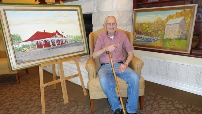 Tim Sedman poses at home with a few of his paintings.