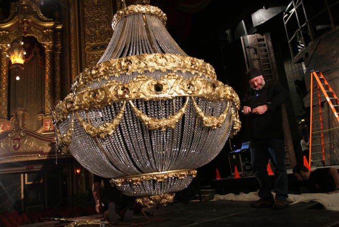 Paul Whittaker of the stage crew works on a giant chandelier for "The Phantom of the Opera," which begins its national tour in Providence.