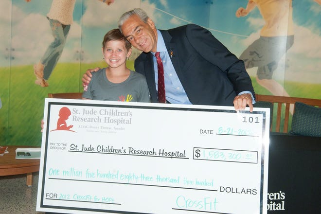 Kate Foster and Rick Shadyac, CEO of the American Lebanese Syrian Associated Charities, pose with an oversize $1.5 million check in August 2012 for St. Jude Children's Research Hospital. The check, presented before Kate became a patient at St. Jude's, was from a joint fundraiser between CrossFit and St. Jude.