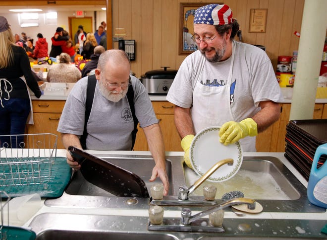 Bob Dermont left, and Mike Simpson wash dishes during the dinner. Simpson’s wife, Jacque, joked that this is the one day of the year her husband washes dishes.