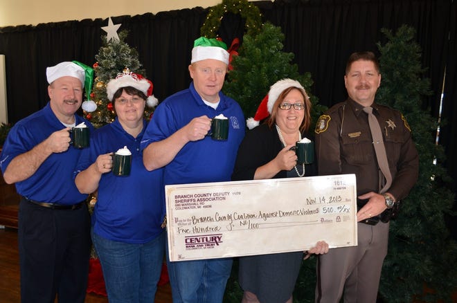 Branch County Sheriff deputy Steve McManamey presents a $500 check to Kim Hemker while Coach Eby Center volunteers Mike Gatke with Dave and Sherry Anderson enjoy a cup of hot chocolate