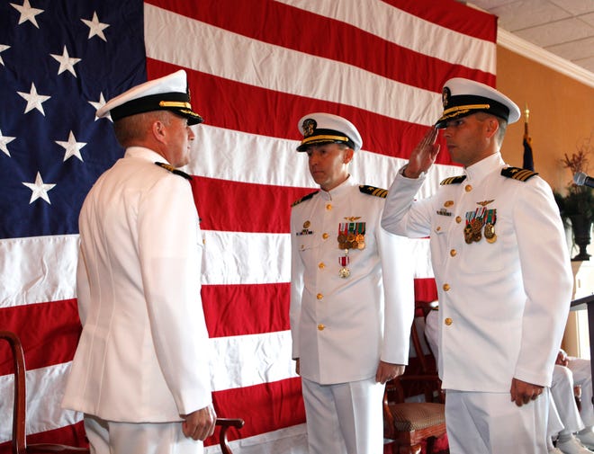 Cmdr. George J. Austin, incoming commanding officer of Helicopter Maritime Strike Weapons School Atlantic salutes Capt. Glenn C. Doyle, Commander, Helicopter Maritime Strike Wing, U.S. Atlantic Fleet as outgoing CO Cmdr. Raymond B. Marsh III stands at his side. Austin assumed command on Nov. 22 during a change of command ceremony at Ocean Breeze Conference Center.