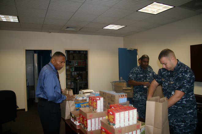 From left, Aaron Jefferson Jr., RP2 Franklin Dippy (partially hidden), LS2 Brayell Jones, and Chaplain Lt. Nathan Boon put together Thanksgiving baskets. Jefferson is the Chapel's Chaplain Religious Enrichment Development Operation facilitator.