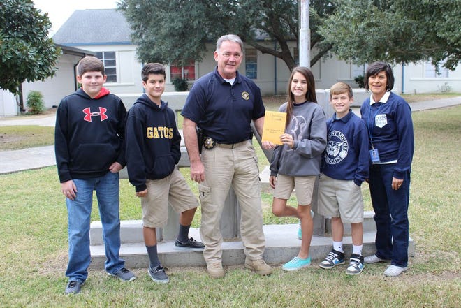 Pictured are Austin Arceneaux, Cameron Benoit, Ssgt. Joey Meyers, Megan Benoit, Cade Conyers, and Arlene Marchand presenting their donation to the Ascension Parish Sheriff’s Office Christmas Crusades program.