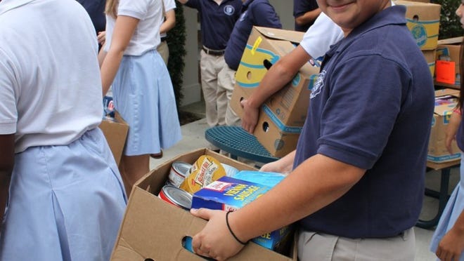 George Kaplanidis (8th grade) loads food Wednesday with other Rosarian Academy 7th and 8th grade students to help feed needy families this Thanksgiving.