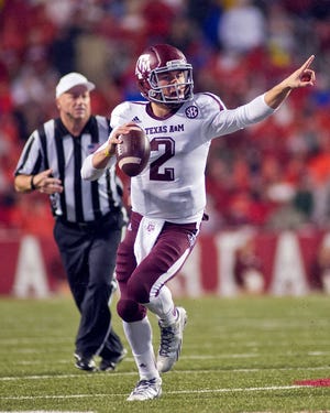 FILE - In this Sept. 28, 2013, file photo, Texas A&M quarterback Johnny Manziel points as he looks to make a pass during an NCAA college football game against Arkansas in Fayetteville, Ark. Manziel has put up eye-popping numbers similar to and in some cases better than he did a year ago, but most polls don't have him favored to join Archie Griffin as the second two-time Heisman winner. (AP Photo/Beth Hall, File)