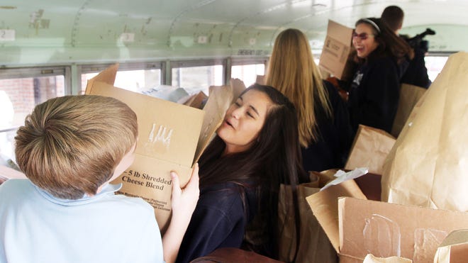 Maria Howard, center, takes a box of food as Annuciation Catholic School students load donations of food on the school's activity bus as part of the Fill the Bus food drive for the Havelock-Cherry Point Ministerial Outreach Association's food pantry on Monday. The two-week campaign, which started as a simply food drive from the school's Interact Club, turned into an all-out campaign to supply the pantry with food in time for Thanksgiving.