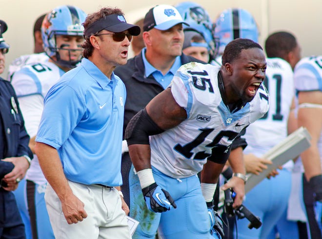 A.J. Blue (15) yells encouragement to teammates during a recent UNC game with head coach Larry Fedora by his side