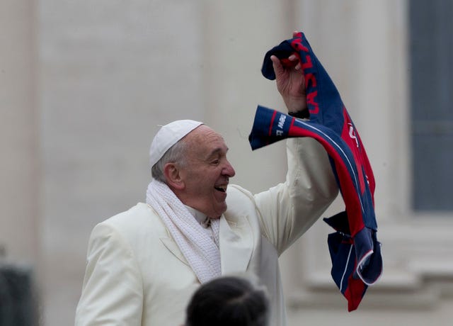 Pope Francis grabs a shirt thrown to him by faithful as he leaves at the end of his weekly general audience in St. Peter's Square at the Vatican, Wednesday, Nov. 27, 2013. A chilly Pope Francis has cheered the thousands of pilgrims who braved a cold snap belting Italy to attend his weekly general audience, saying they were courageous to come out. (AP Photo/Alessandra Tarantino)