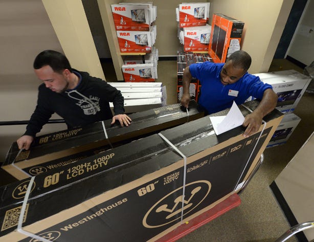 Kmart employees Joe Glazebrook, left, and Dwan Wilkins, right, load two 60 inch televisions on a cart shortly after the doors opened at 6 a.m. on Thanksgiving morning in Burlington. Photo by Sam Roberts / Times-News