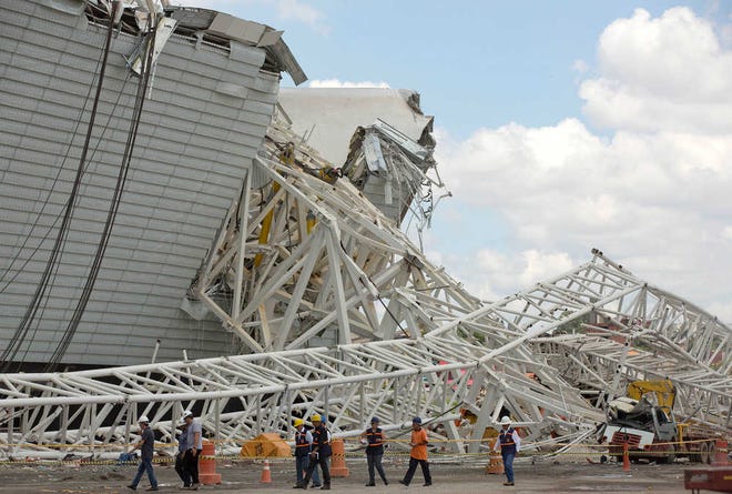 Civil defense and policemen inspect the damage of an accident at the Arena Corinthians, known locally as the Itaquerao, that will host the 2014 World Cup in Sao Paulo, Brazil, Thursday, Nov. 28, 2013. Two workers were killed when a crane crashed into a 500-ton metal structure that toppled over part of the stadium Wednesday, aggravating already urgent worries that Brazil won't be ready for soccer's showcase event next year. (AP Photo/Andre Penner)