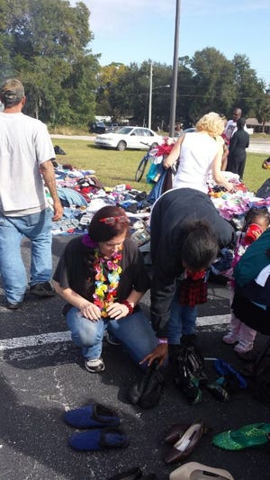 Susan Burris, with a lei around her neck, looks over some shoes given out by Comes As You Are Ministry in the parking lot of Trinity Assembly of God church in Fruitland Park on Saturday.