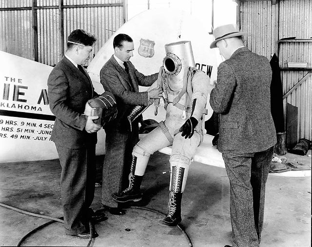 Wiley Post helps fit a parachute harness to his inflated his pressure suit. Post, a former stunt parachute jumper with a patch-covered eye, took off from the Bartlesville airstrip and flew to the edge of the stratosphere — a flying first — on Dec. 7, 1934.