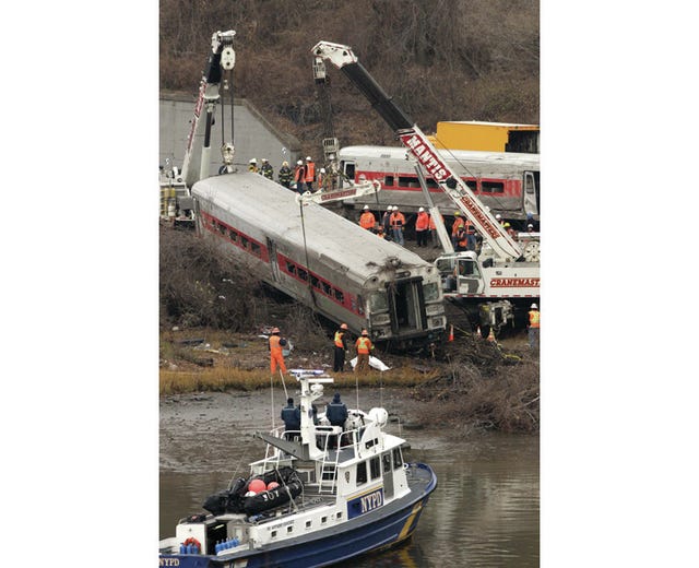 Cranes salvage the last car from from a train derailment in the Bronx section of New York, Monday, Dec. 2, 2013. Federal authorities began righting the cars Monday morning as they started an exhaustive investigation into what caused a Metro-North commuter train rounding a riverside curve to derail, killing four people and injuring more than 60 others. A second “event recorder” retrieved from the train may provide information on the speed of the train, how the brakes were applied, and the throttle setting, a member of the National Transportation Safety Board said Monday. AP Photo/Mark Lennihan 
 Cranes salvage the last car from from a train derailment in the Bronx section of New York, Monday, Dec. 2, 2013. 
 In this Dec 1, 2013 photo provided by the National Transportation Safety Board, NTSB investigator George Haralampopoulous hands a data recorder down to Mike Hiller from the derailed Metro-North train in the Bronx borough of New York. Two data recorders from the commuter train that derailed while rounding a riverside curve, killing four people, may provide information on the speed of the train, how the brakes were applied and the throttle setting, a member of the NTSB said Monday. The NTSB was downloading data from a recorder previously found in the rear locomotive in the train that derailed Sunday in New York. A second recorder was found in the front car of the train and has been sent to Washington for analysis, NTSB board member Earl Weener said. AP Photo/NTSB