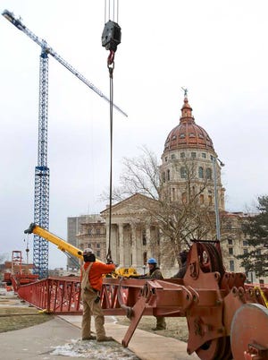 Construction crews battle through the cold Thursday afternoon to attach cables to a crane that will take apart the tower crane at the Statehouse. The tower crane is scheduled to be taken down on Friday. The crane has been operational since September 2010.